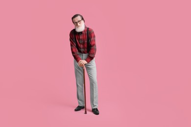 Senior man with walking cane on pink background