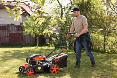 Man cutting green grass with lawn mower in garden