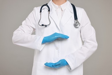 Photo of Doctor with stethoscope holding something on grey background, closeup