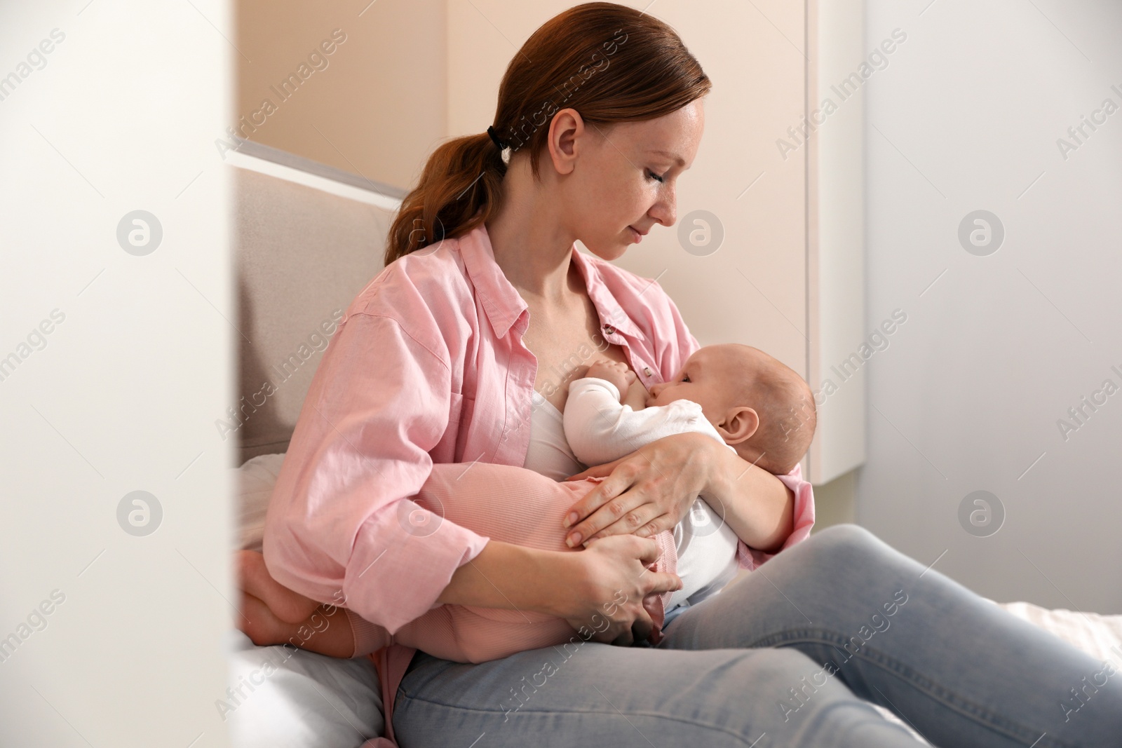 Photo of Young woman breast feeding her little baby in bedroom