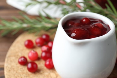 Photo of Fresh cranberry sauce in pitcher on table, closeup. Space for text