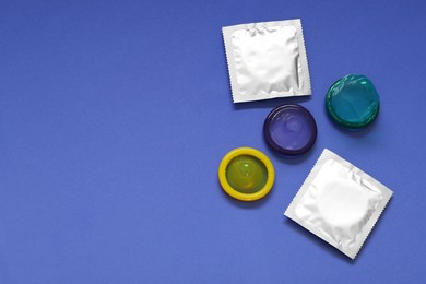 Photo of Unpacked condoms and packages on blue background, flat lay with space for text. Safe sex