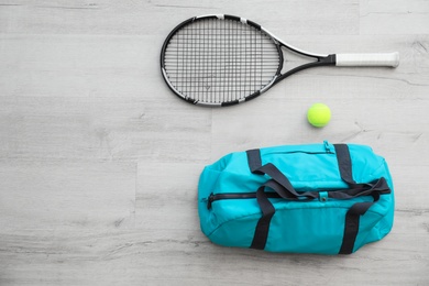 Photo of Sports bag, racket and ball on wooden floor, top view