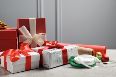 Photo of Beautiful Christmas gift boxes wrapped in paper and decorated with bows on light table
