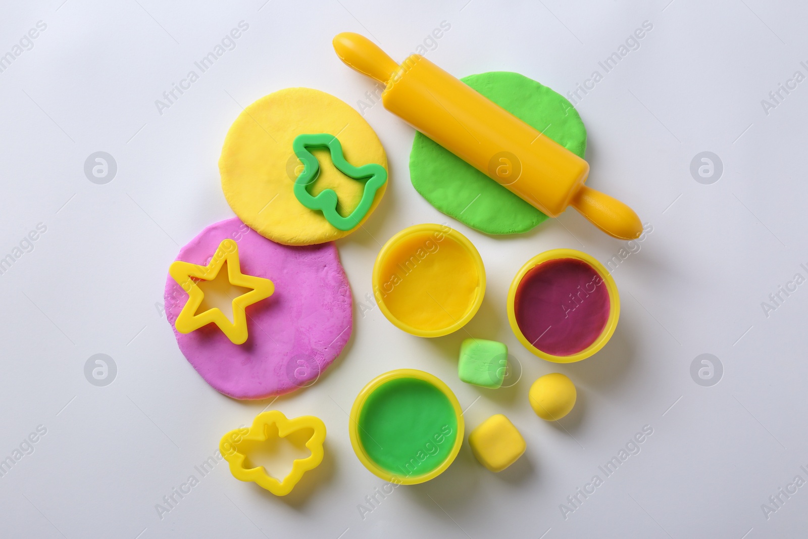 Photo of Set of tools and color play dough on white background, top view