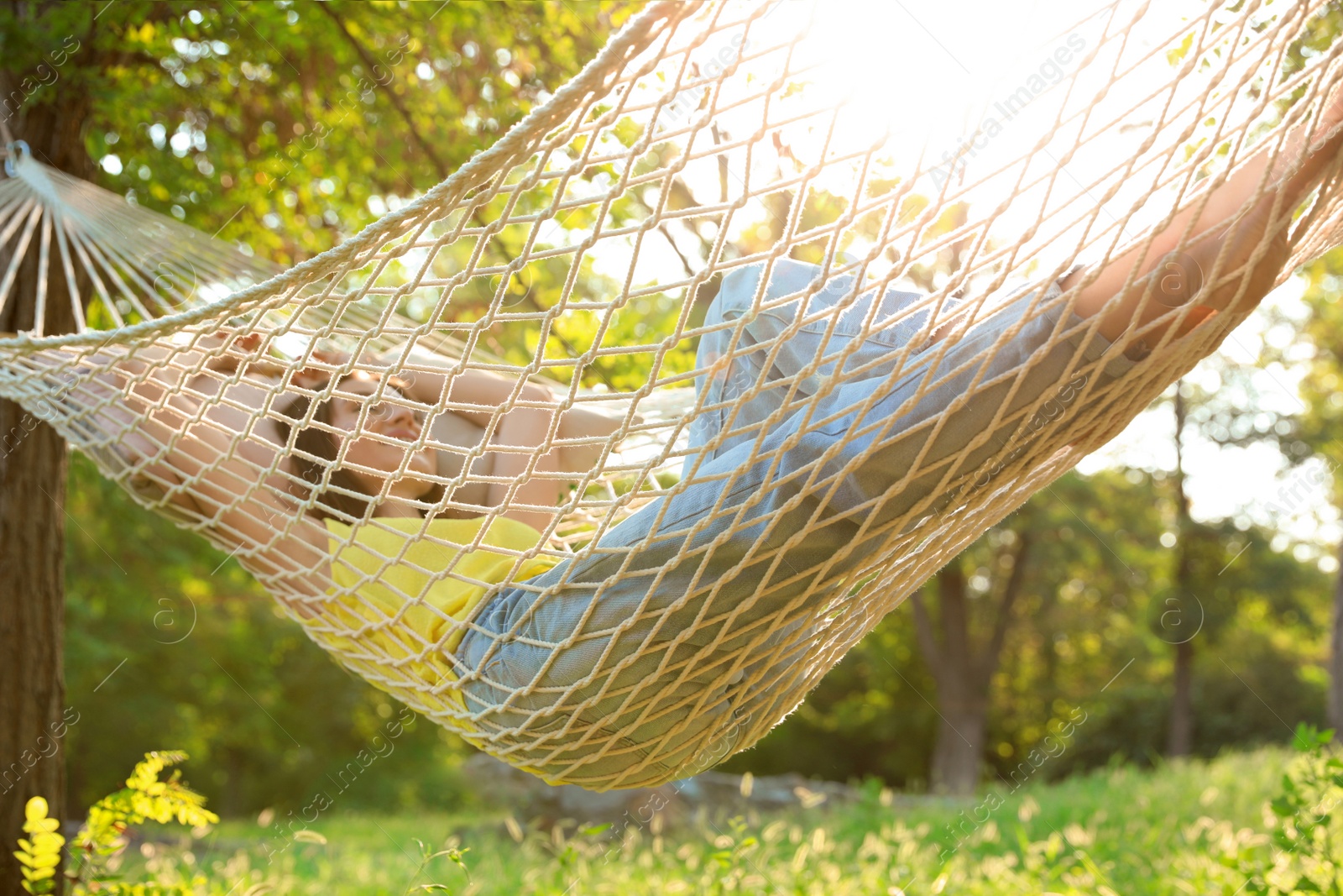 Photo of Young woman resting in comfortable hammock at green garden