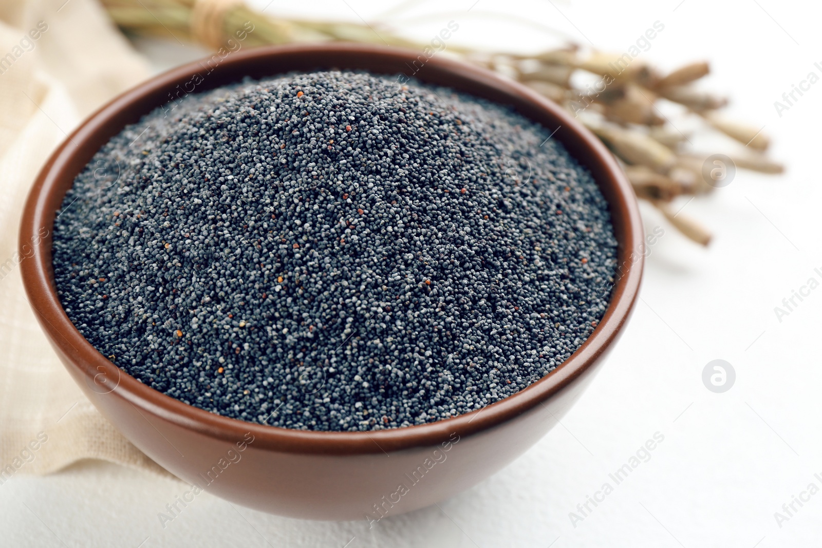Photo of Poppy seeds in bowl on white table