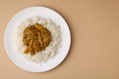 Photo of Delicious chicken curry with rice on beige background, top view. Space for text