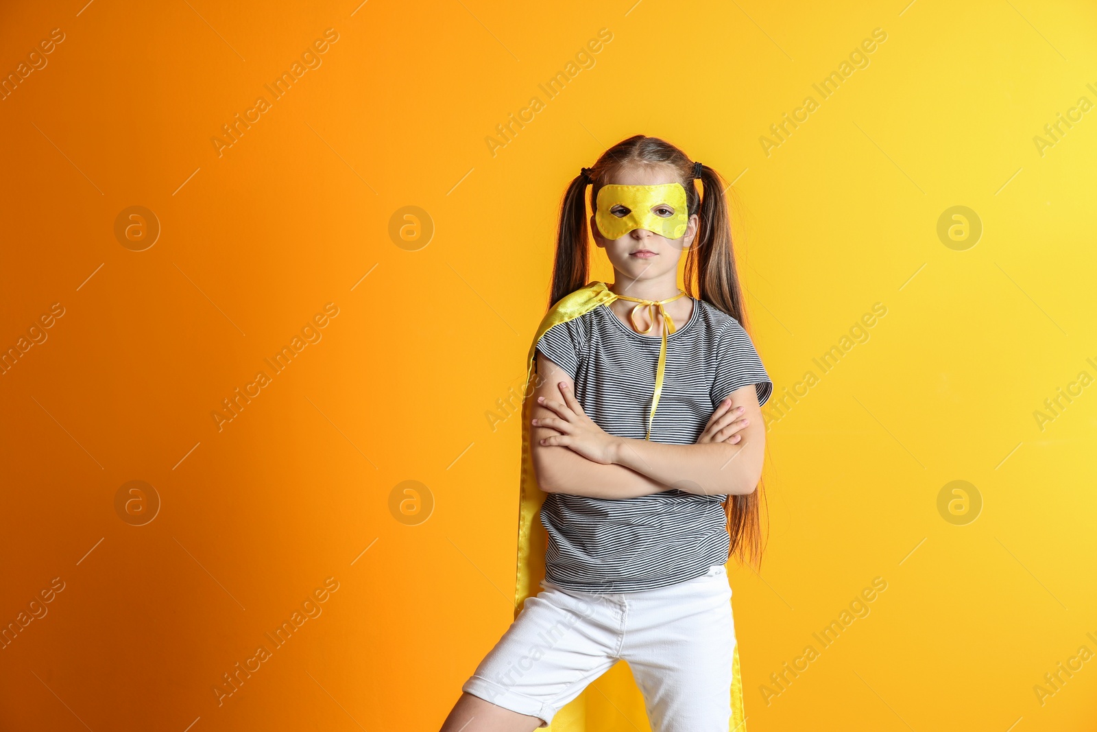 Photo of Adorable little child playing superhero on color background. Indoor recreation