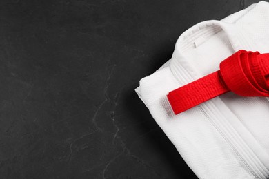 Photo of Red karate belt and white kimono on gray background, top view. Space for text