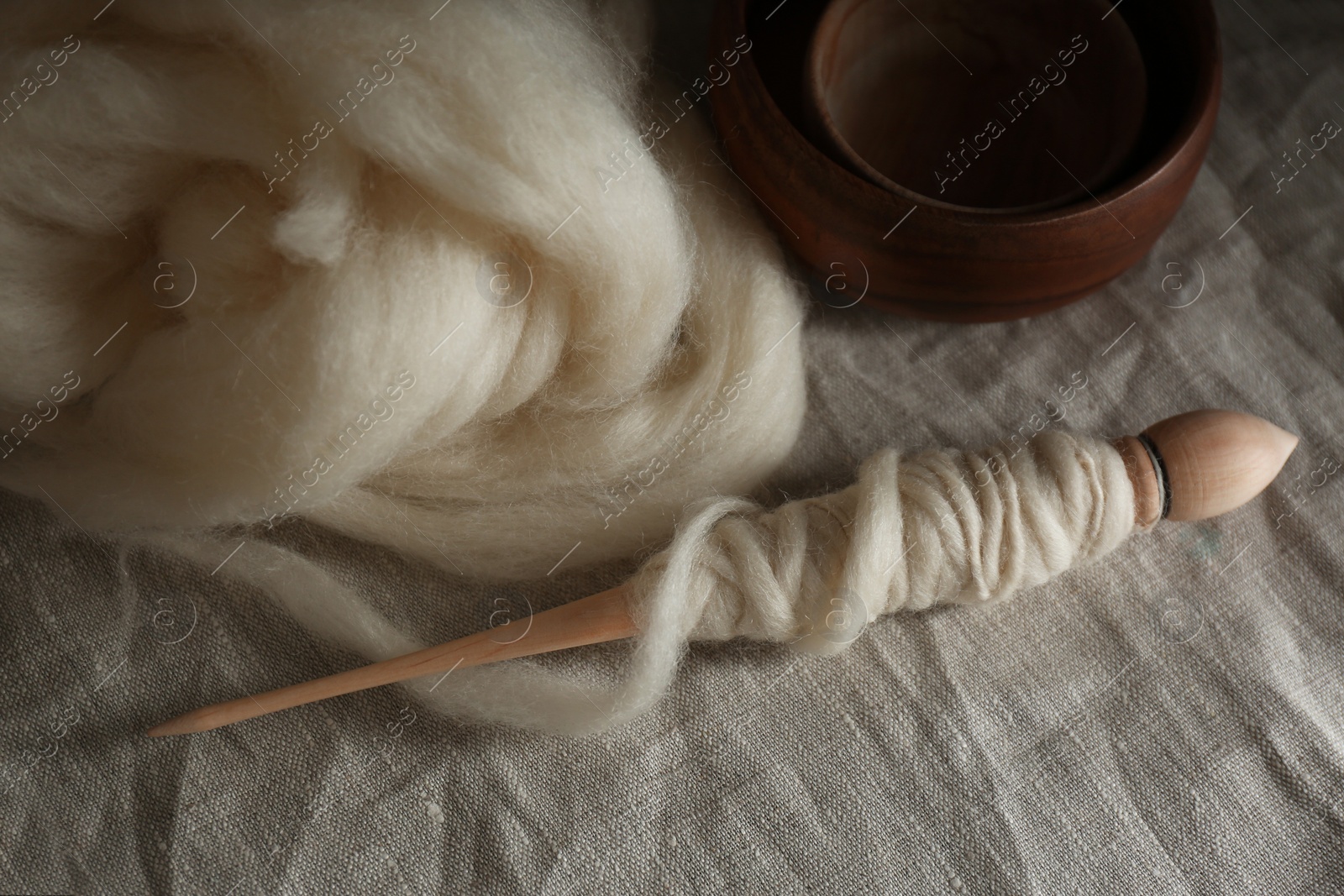 Photo of Soft white wool and spindle on table, above view