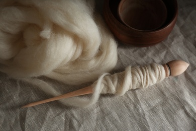 Photo of Soft white wool and spindle on table, above view