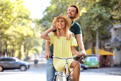 Happy couple riding bicycle together on street