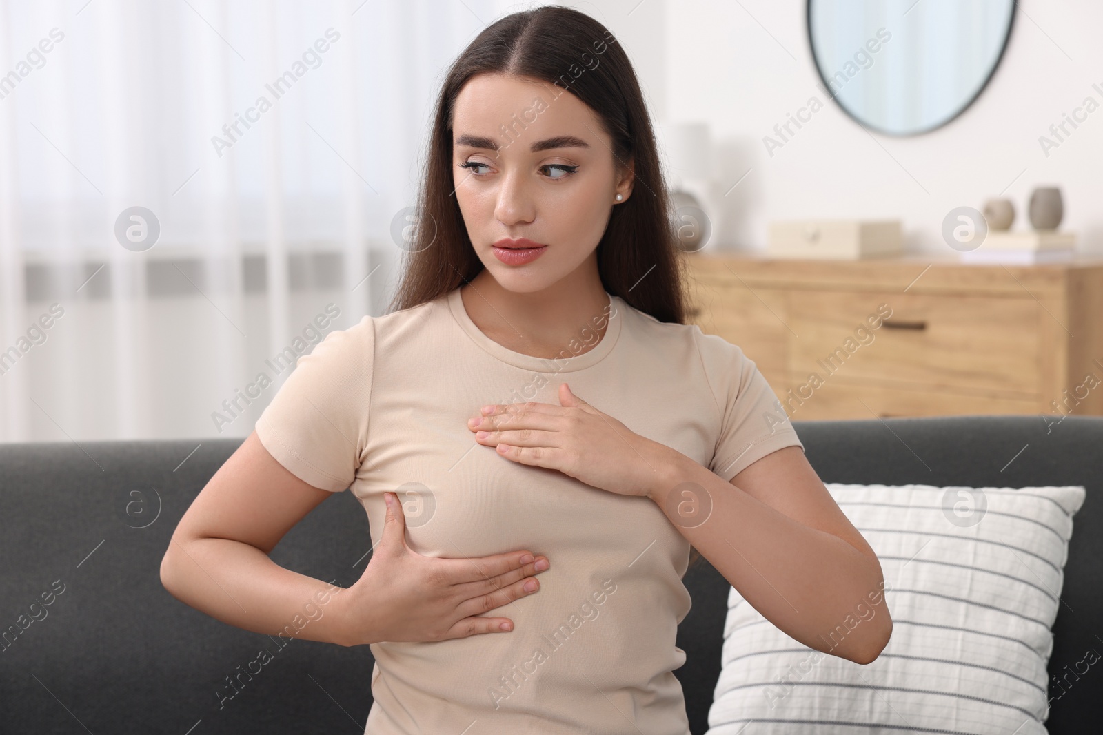 Photo of Beautiful young woman doing breast self-examination at home