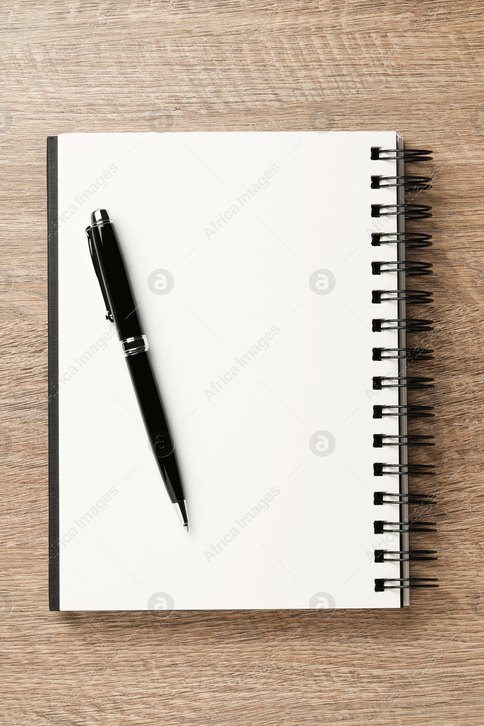 Photo of Notebook and pen on wooden table, top view