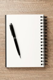 Notebook and pen on wooden table, top view