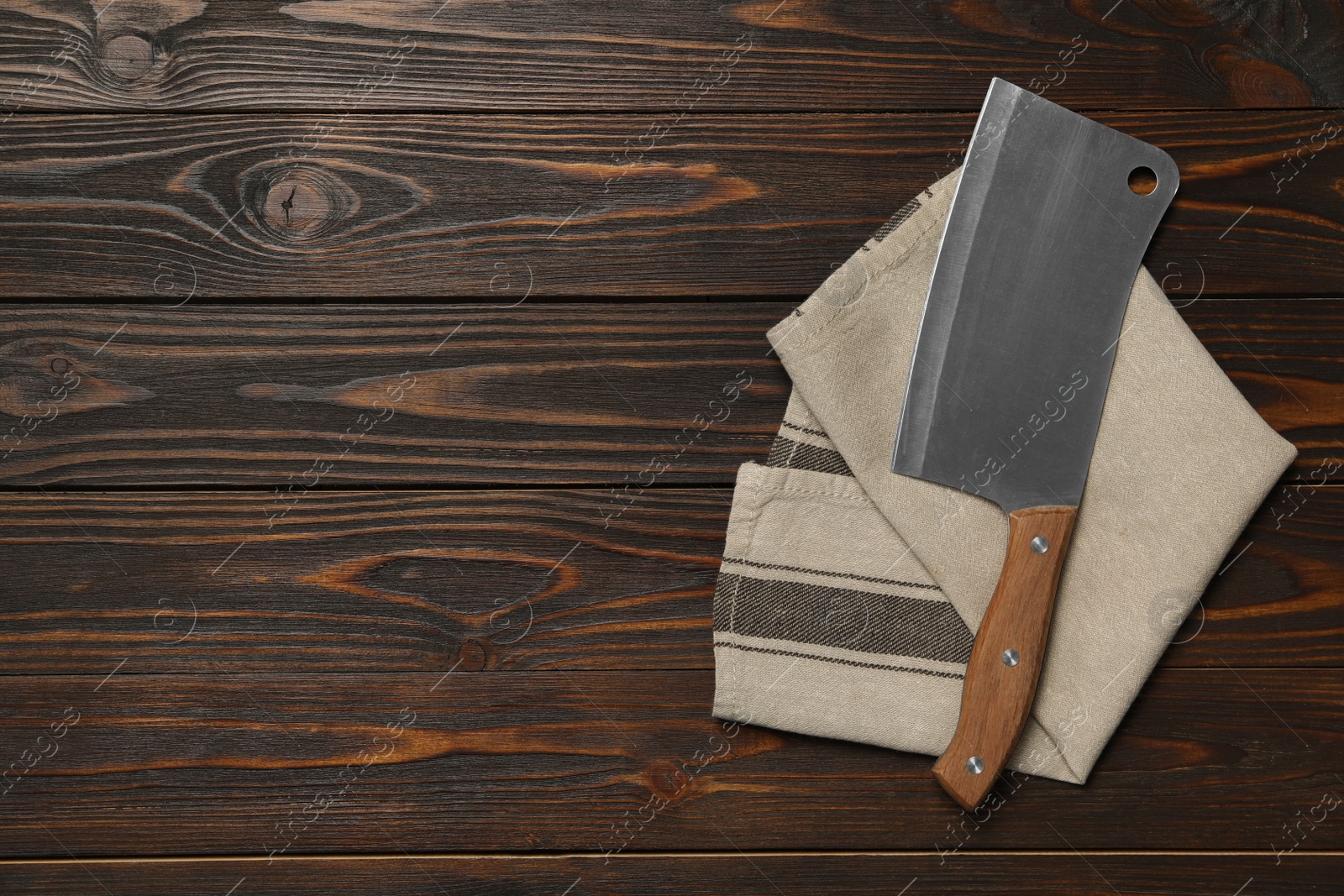 Photo of Modern cleaver and kitchen towel on brown wooden table, flat lay with space for text. Cooking utensils