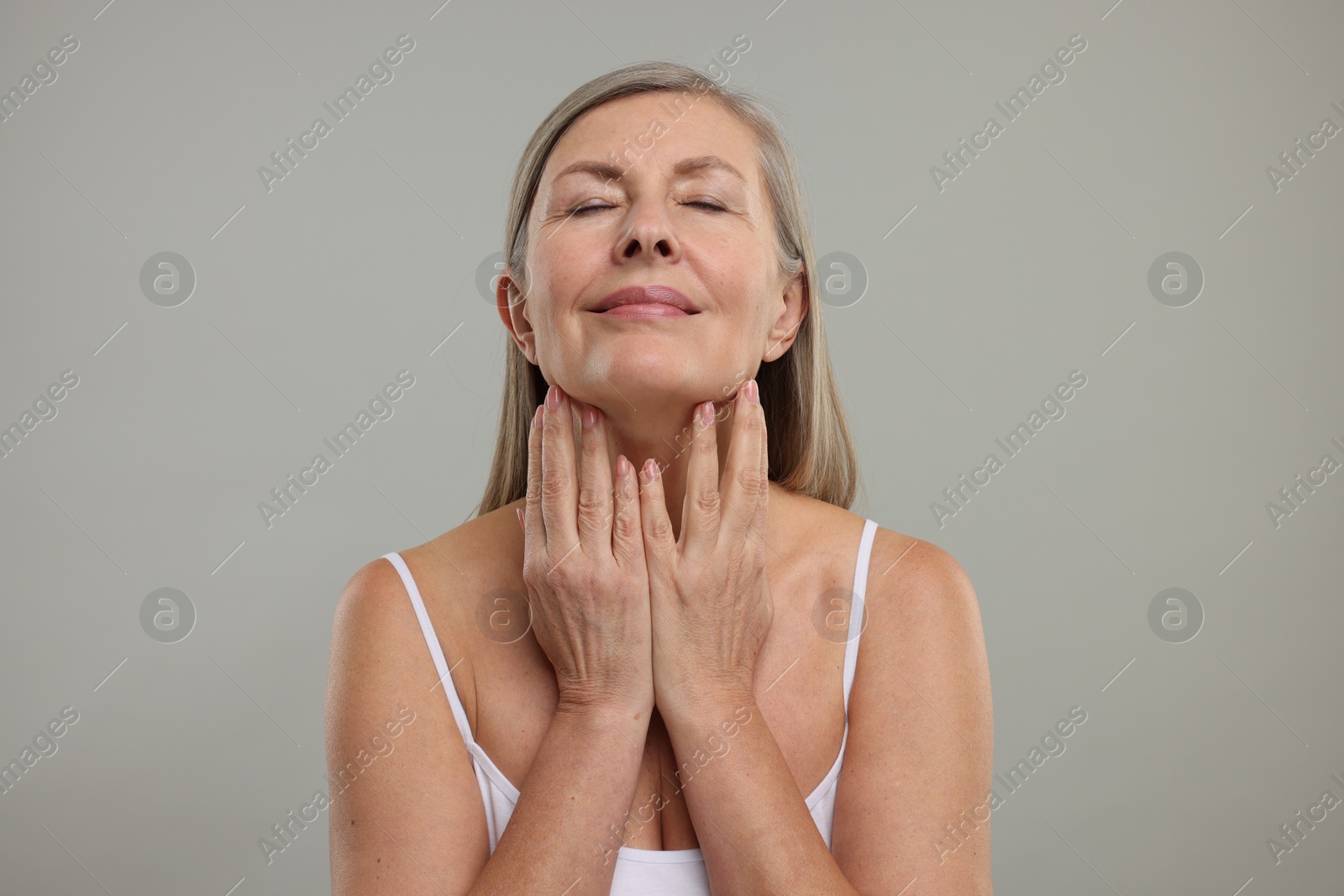 Photo of Beautiful woman touching her neck on grey background