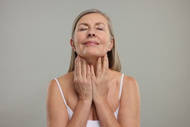 Beautiful woman touching her neck on grey background