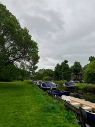 Beautiful view of green lawn near city canal with different boats