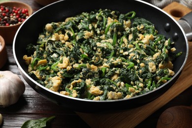 Photo of Tasty spinach dip with eggs in dish served on wooden table, closeup