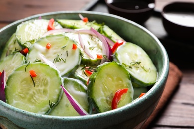 Photo of Dish with fresh creamy cucumber salad on table, closeup