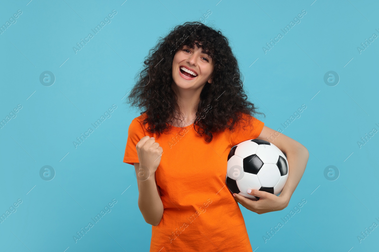 Photo of Happy fan with soccer ball on light blue background