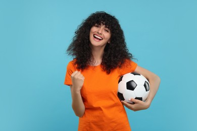 Happy fan with soccer ball on light blue background