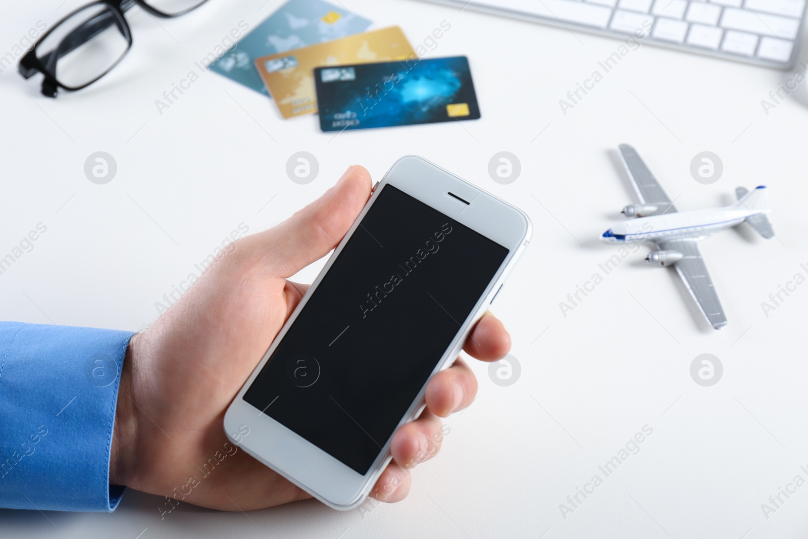 Photo of Man using mobile phone at table in travel agency, closeup. Space for design