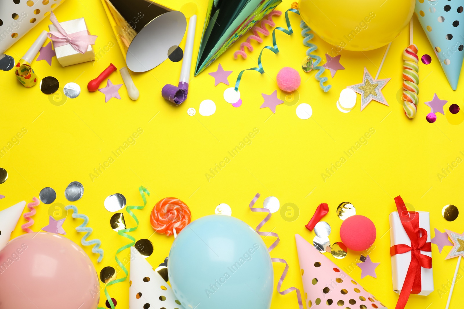 Photo of Flat lay composition with party hats and other festive items on yellow background, space for text. Birthday surprise