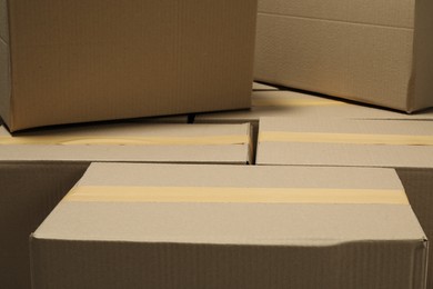 Photo of Many closed cardboard boxes with tape as background, closeup