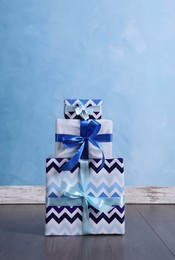 Stack of beautifully wrapped gift boxes near light blue wall indoors