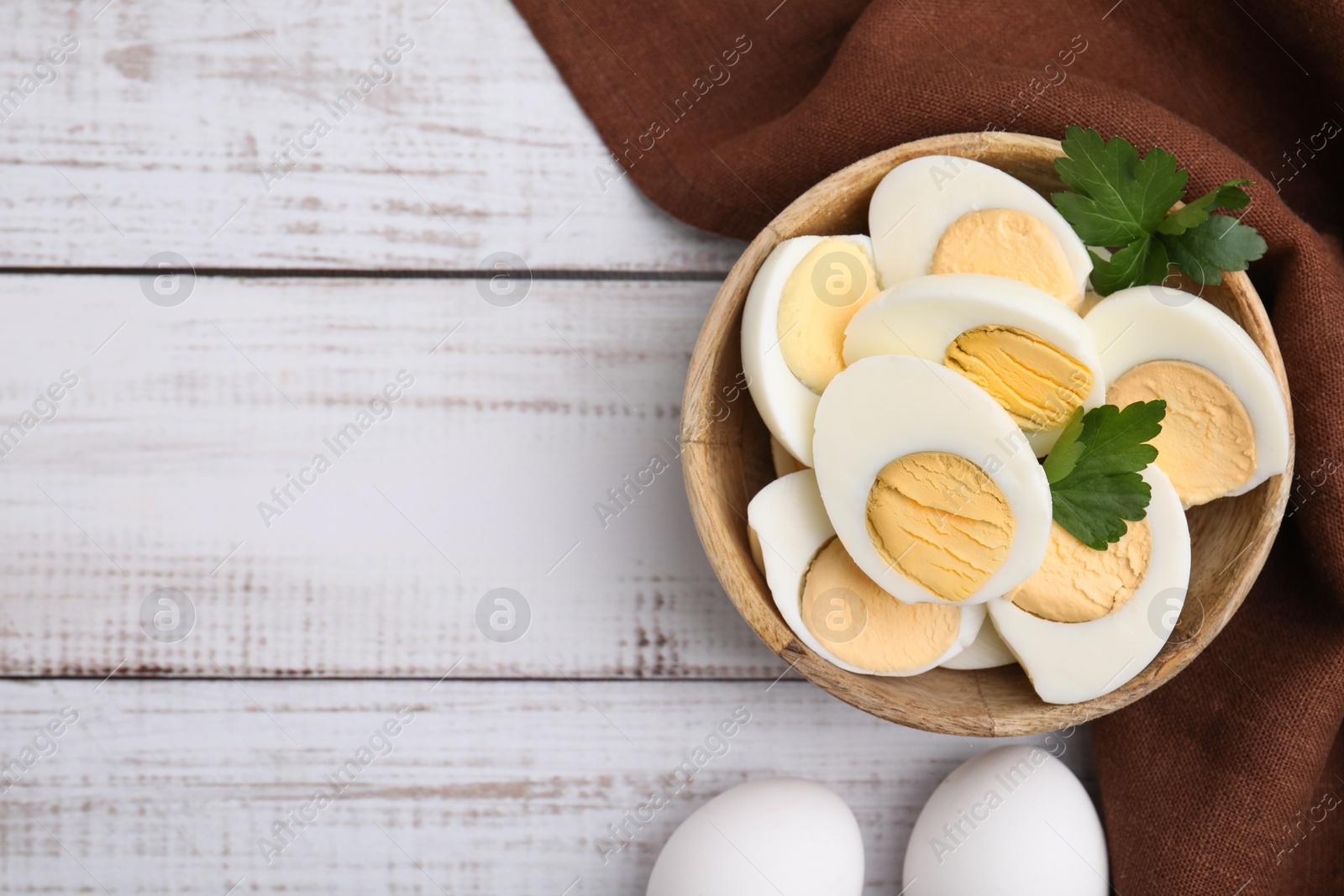 Photo of Fresh hard boiled eggs and parsley on white wooden table, flat lay. Space for text