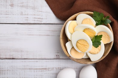 Fresh hard boiled eggs and parsley on white wooden table, flat lay. Space for text