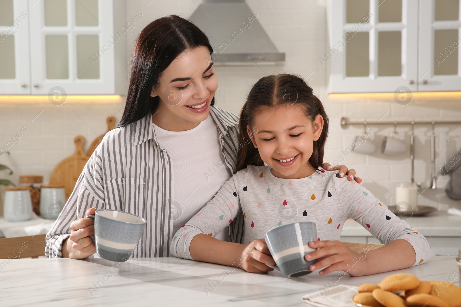 Photo of Happy mother and daughter having breakfast at table in kitchen. Adoption concept