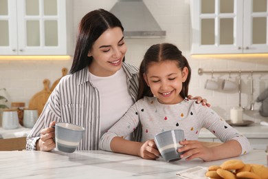 Happy mother and daughter having breakfast at table in kitchen. Adoption concept