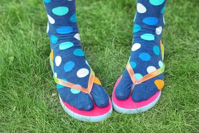 Photo of Woman wearing bright socks with flip-flops standing on grass