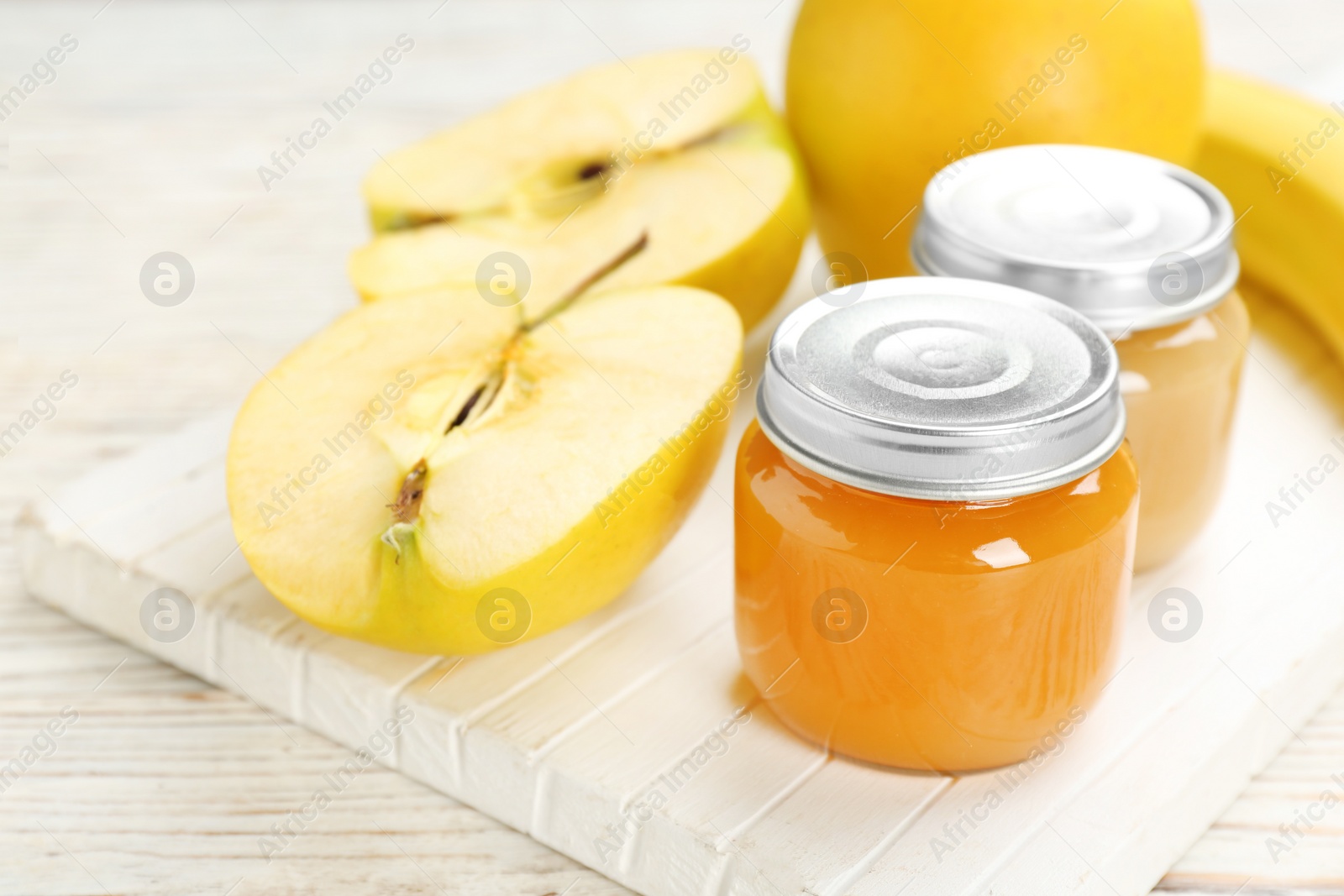 Photo of Jars with healthy baby food and apple on wooden board