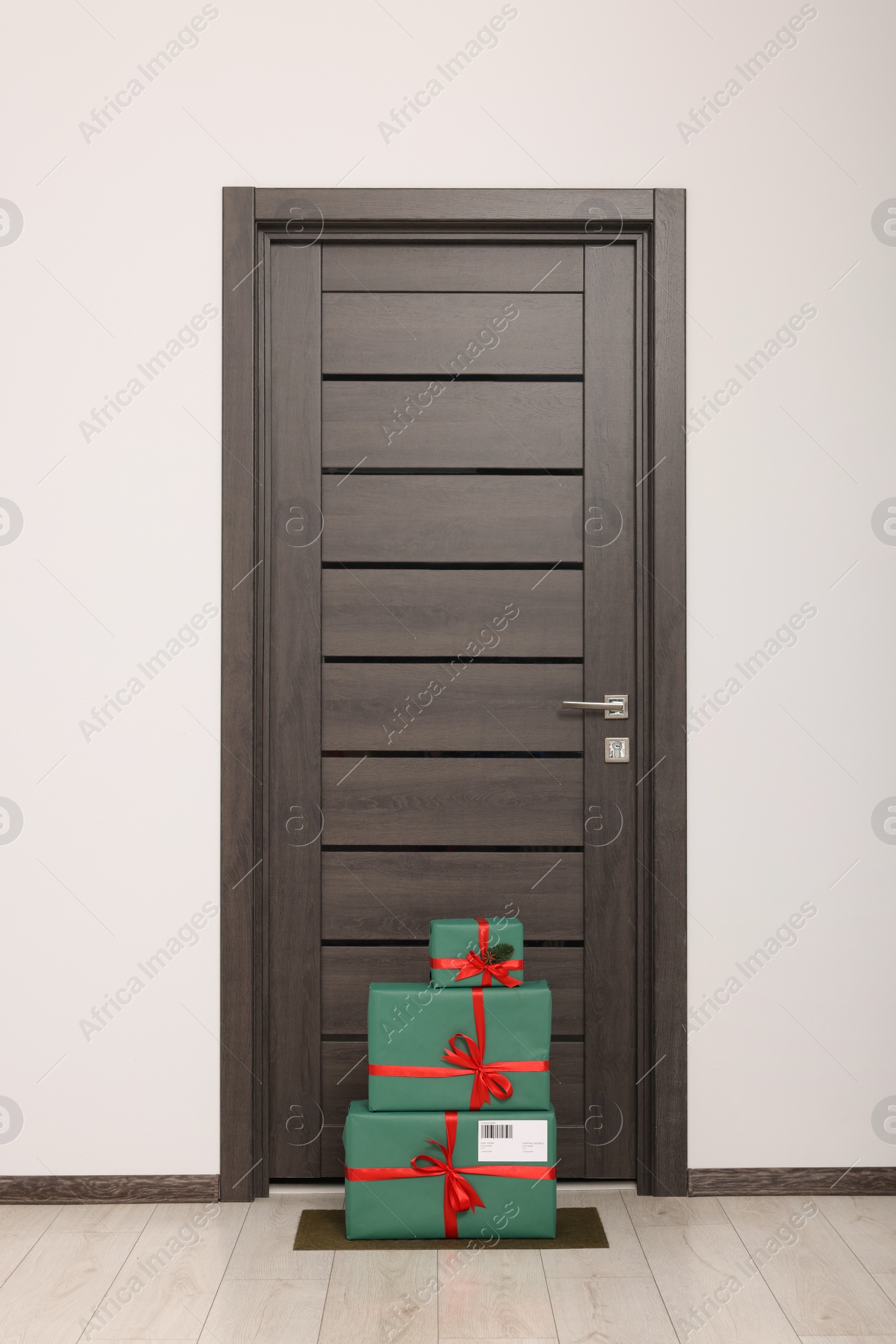 Photo of Christmas gift boxes on floor near door. Sending present by mail