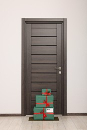 Photo of Christmas gift boxes on floor near door. Sending present by mail