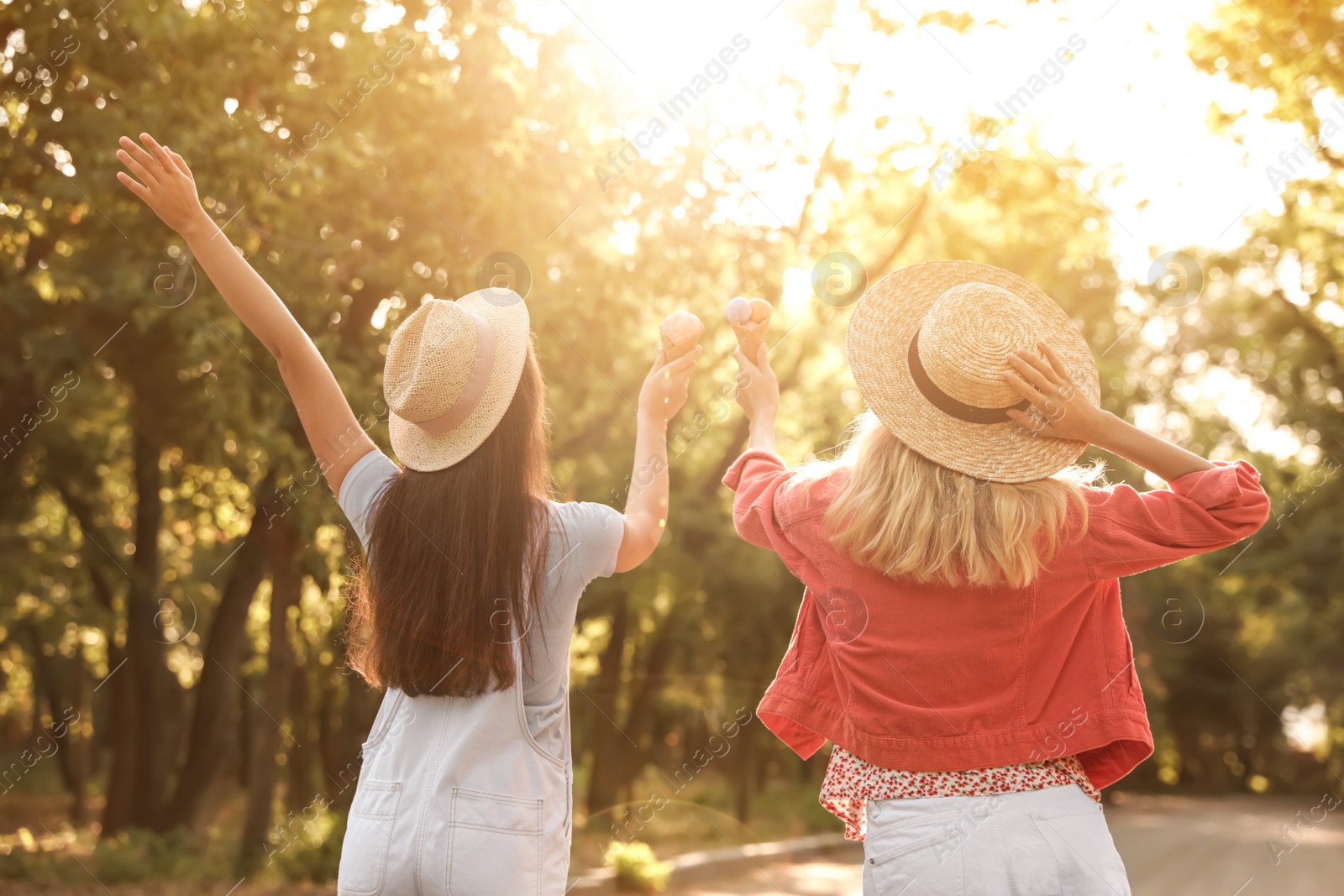 Photo of Young women with ice cream spending time together outdoors, back view