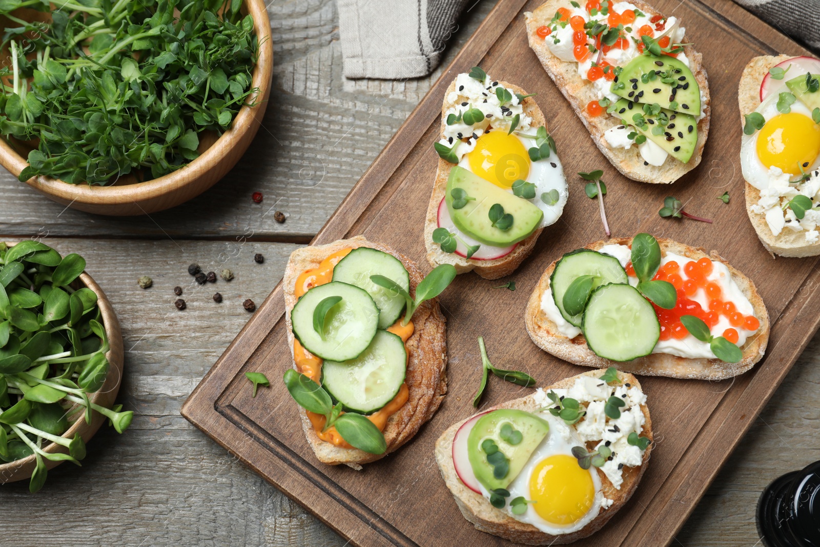 Photo of Different delicious sandwiches with microgreens on wooden table, flat lay