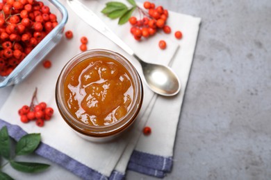 Flat lay composition with delicious rowan jam on grey table. Space for text