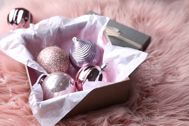 Photo of Beautiful Christmas baubles in box on pink faux fur