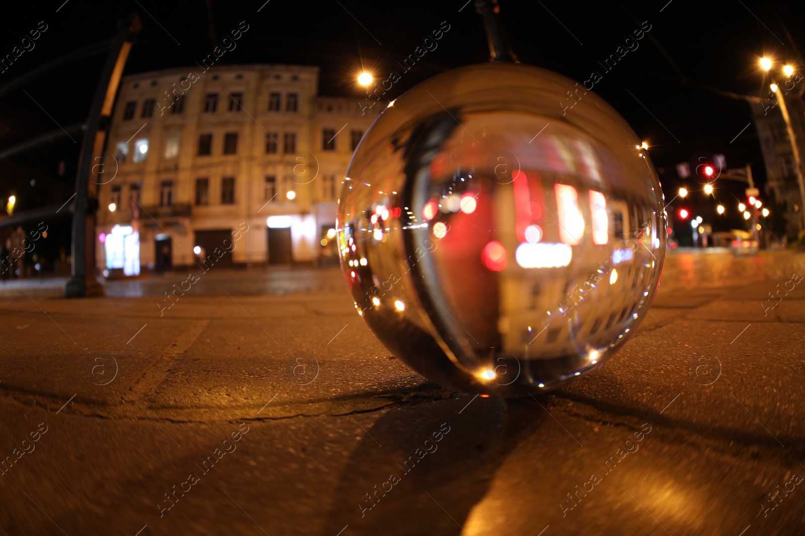 Photo of Crystal ball on asphalt road at night, selective focus. Wide-angle lens