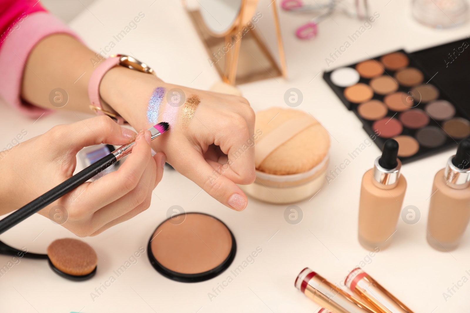 Photo of Beauty blogger doing eyeshadow swatches at table, closeup