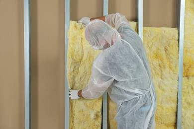 Photo of Worker insulating wall indoors, back view. Space for text