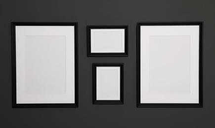 Photo of Empty frames on black wall. Mockup for design