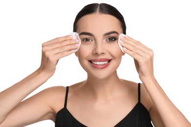 Beautiful woman removing makeup with cotton pads on white background