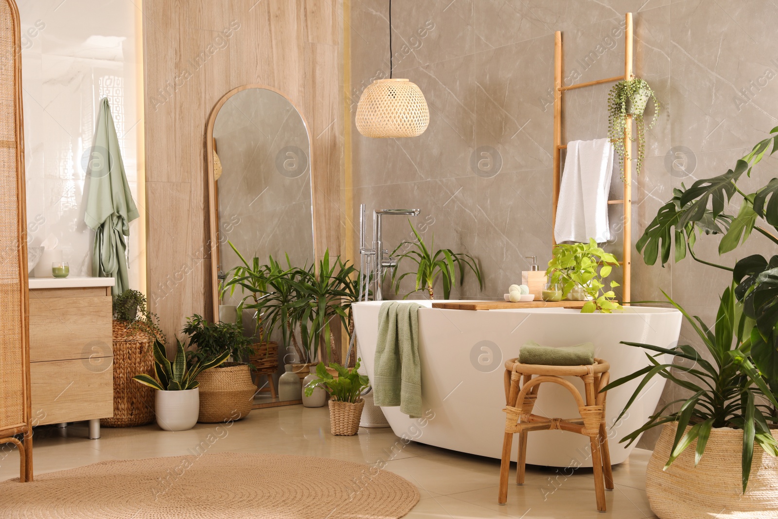 Photo of Modern white tub and beautiful green houseplants in bathroom. Interior design